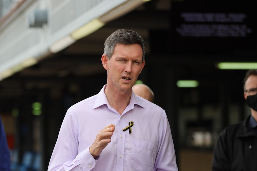 A slim man with short grey hair gesticulates while speaking.