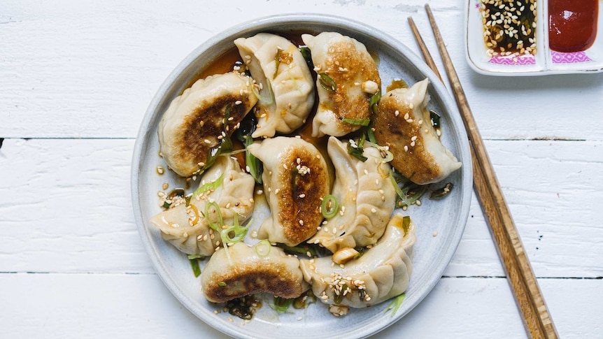 A plate of vegetarian potstickers, dumplings with fried bottoms, on a plate with chilli and soy sauce, a delicious recipe.