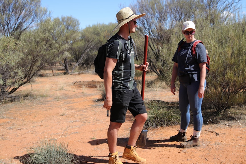 Two young people stand in the outback 