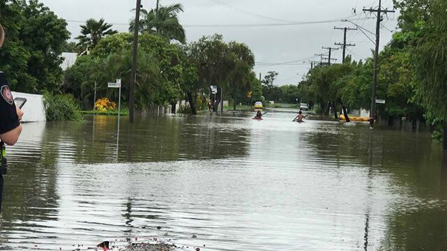 People kayak down flooded street.