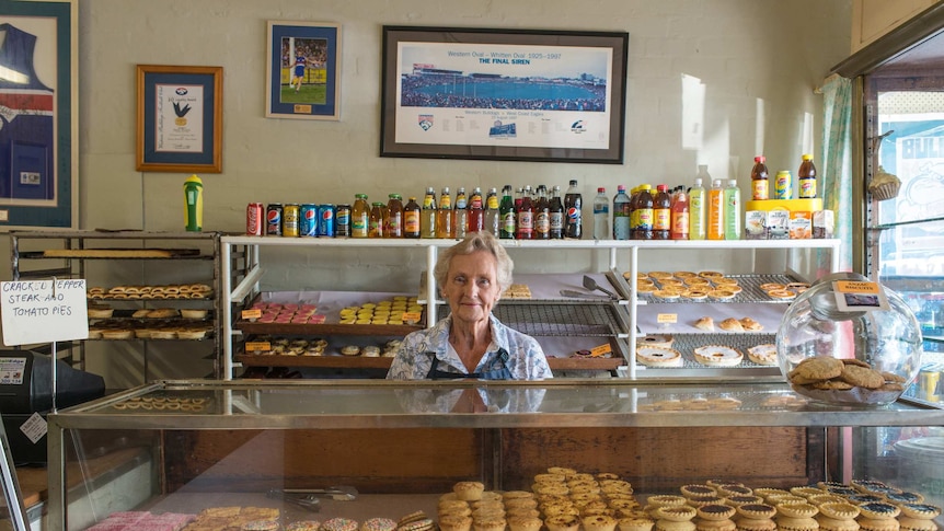 A woman stands behind the counter of a bakery.