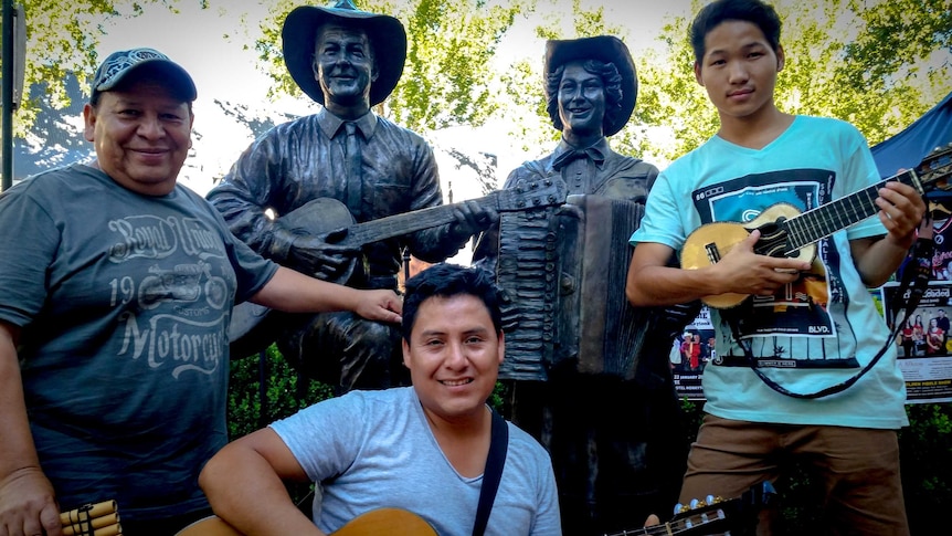 Fily, Felix and Boroo Cuba pose with the bronze statues of Slim Dusty and Joy McKeon