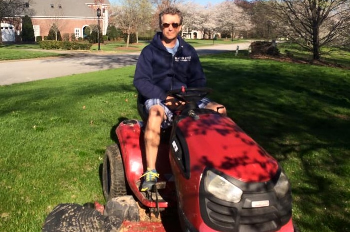 A man sitting on a ride-on lawn mower.