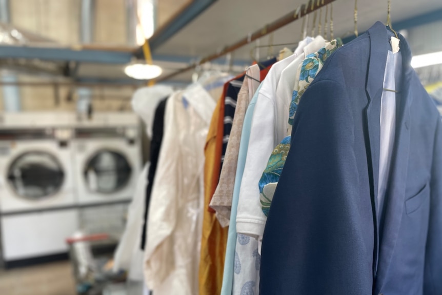 Clothes freshly pressed and steamed are hung up on a clothes hook in the shop