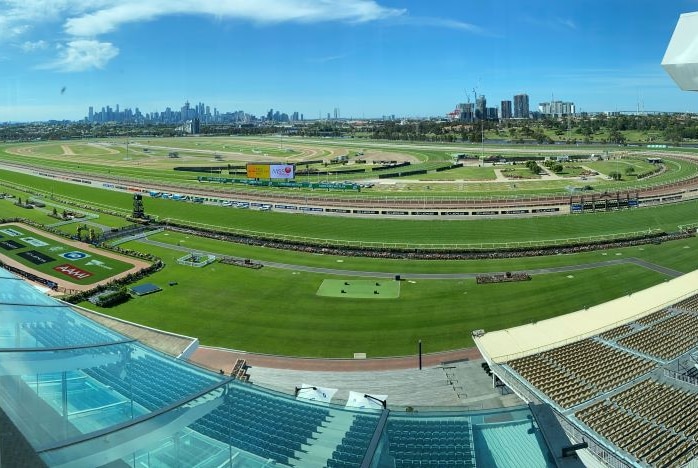 A panoramic shot of a race course, taken from a grandstand, with the Melbourne skyline in the distance.