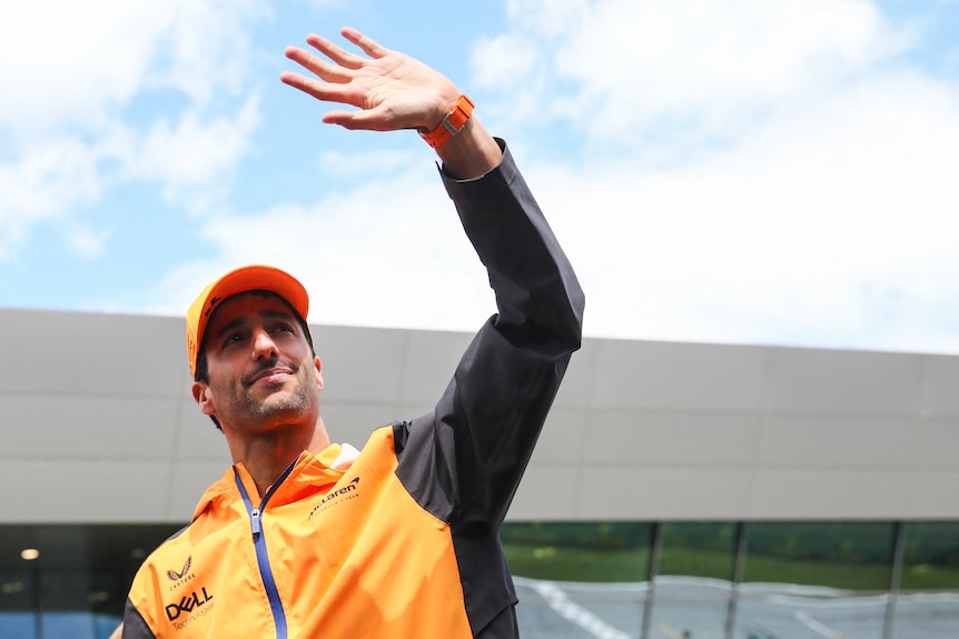 Man in orange and grey uniform waves.