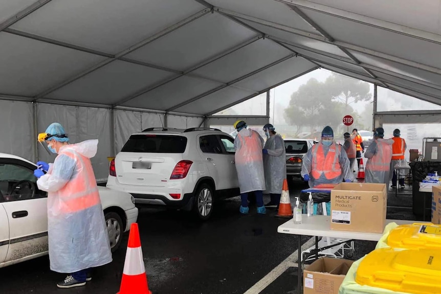 Cars in a drive-through testing facility.