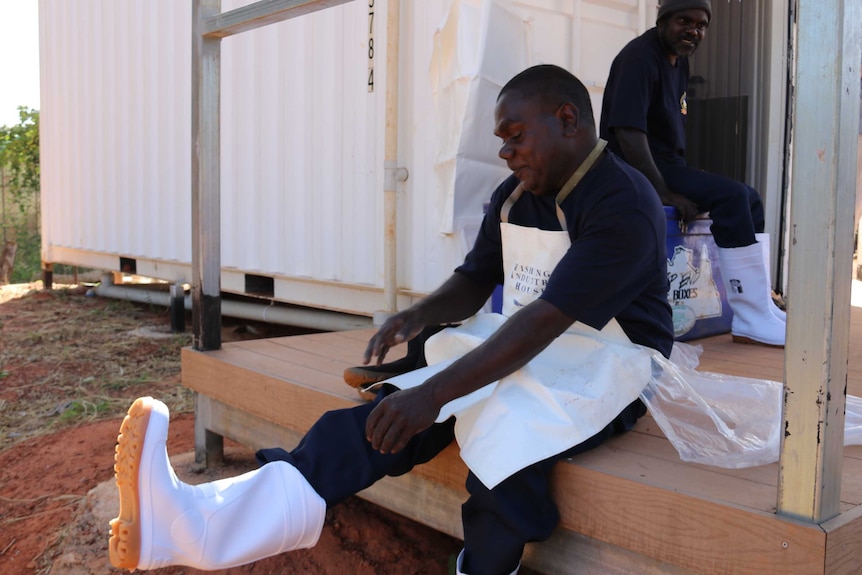 Indigenous fisherman Hans Lawrence puts on white gumboots to wear in the fish processing facility.