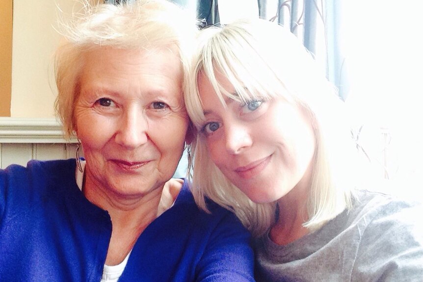 A young woman and an older woman pose together for a selfie.
