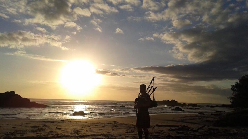 Silhouette of Keith Robinson playing his bagpipes on town Beach in Port Macquarie