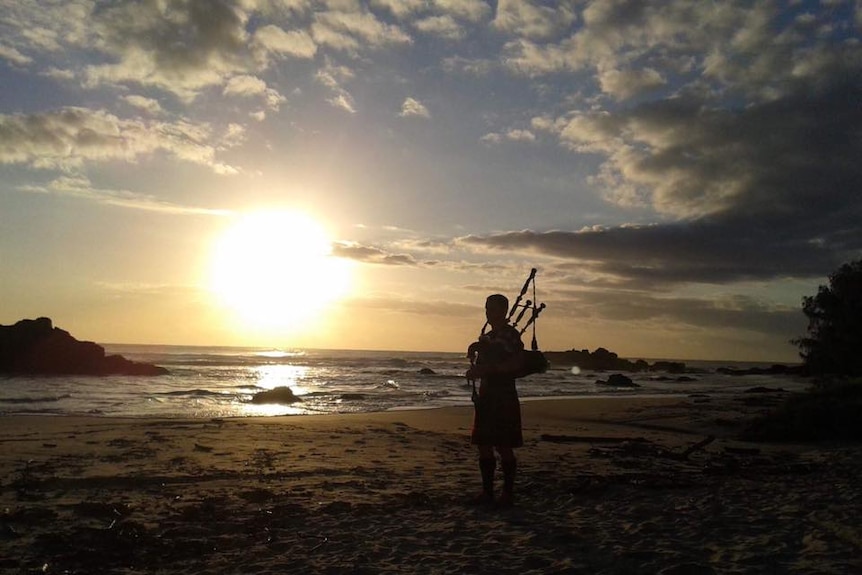 Silhouette of Keith Robinson playing his bagpipes on town Beach in Port Macquarie