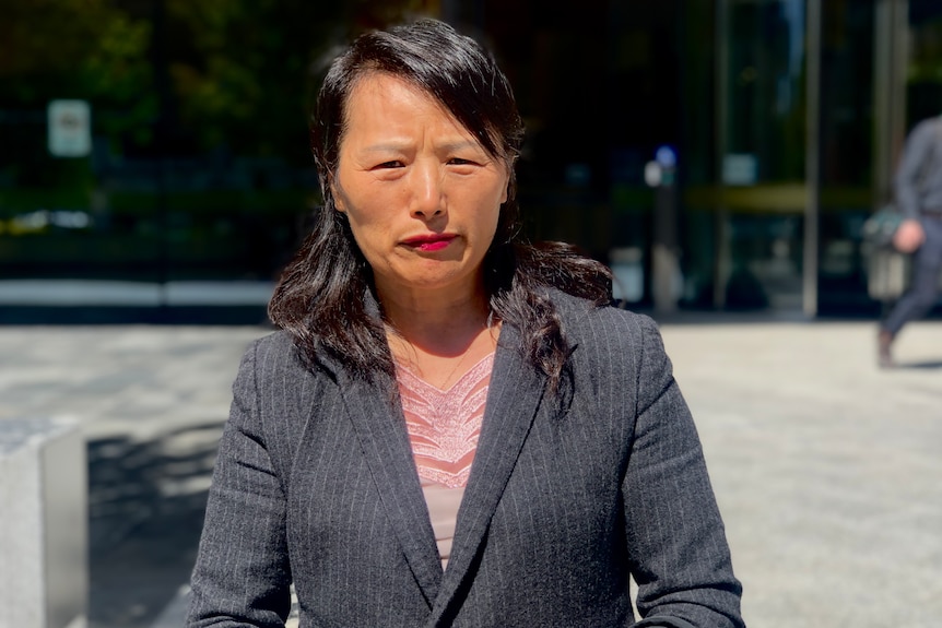 A woman looks serious outside court.