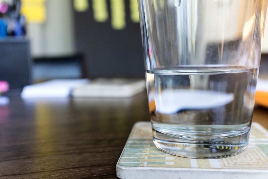 A half-full glass of water sits on a coaster.