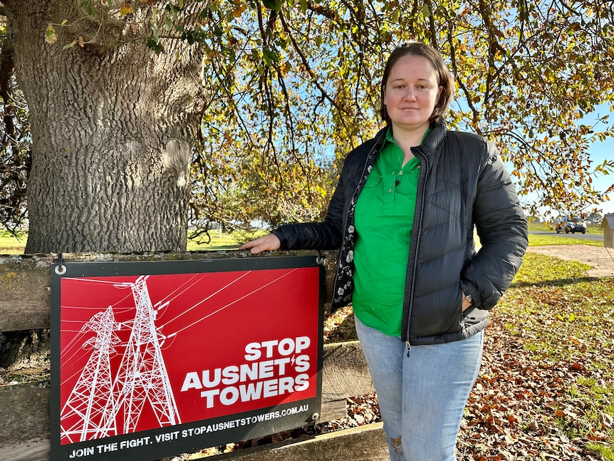 Woman standing beside a sign saying "Stop AusNet's Towers" .