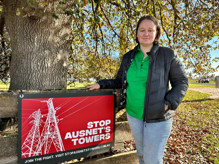 Woman standing beside a sign saying "Stop AusNet's Towers" .