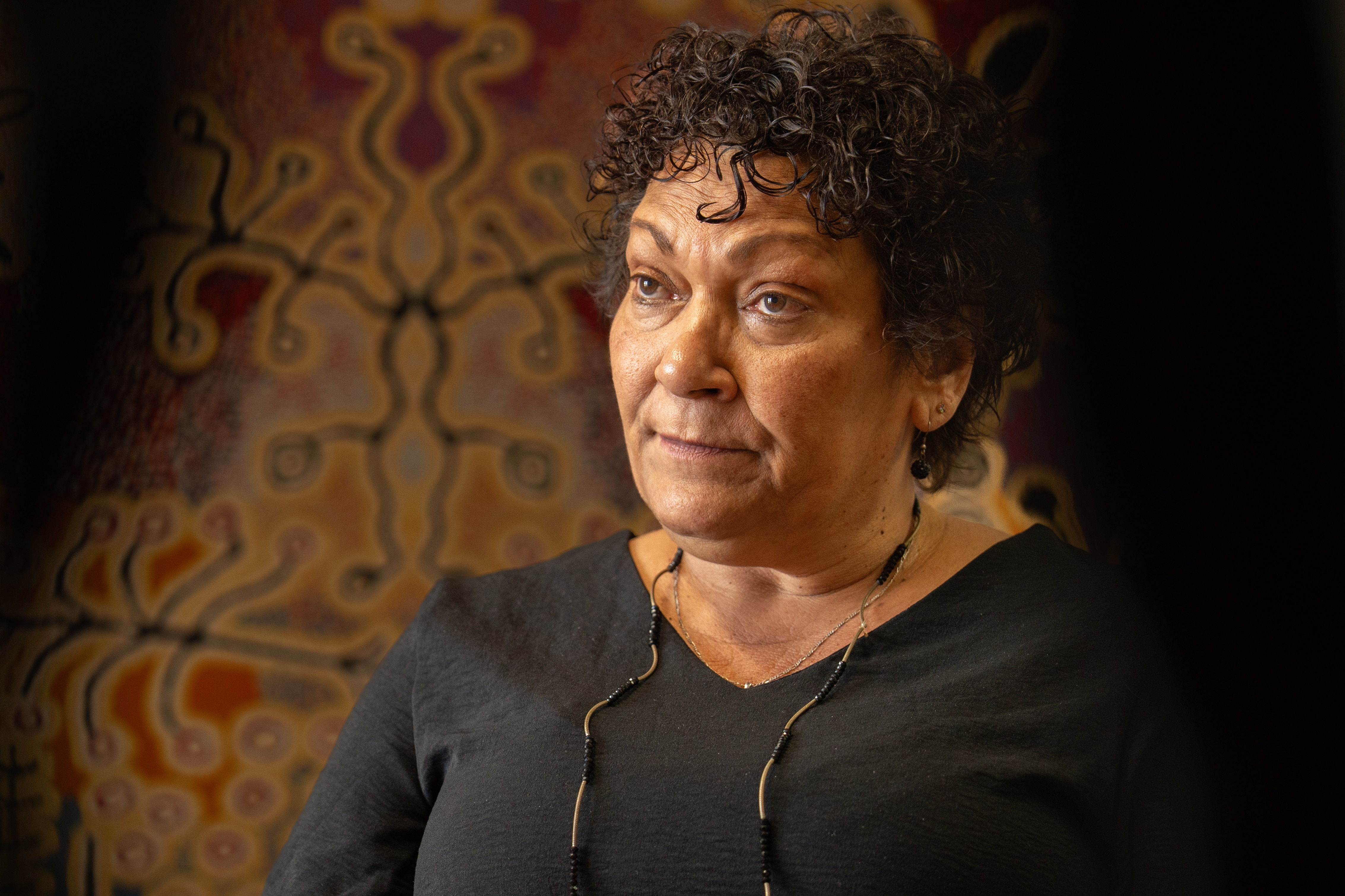 Uma mulher ao lado de uma obra de arte aborígine.