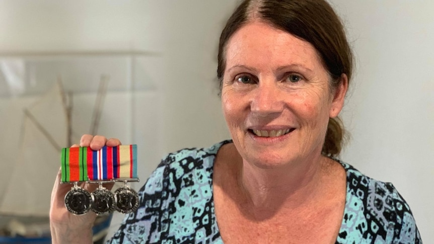 A woman holds replica service medals