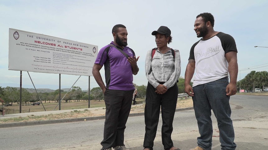 Three Papua New Guinea University students stand on a street