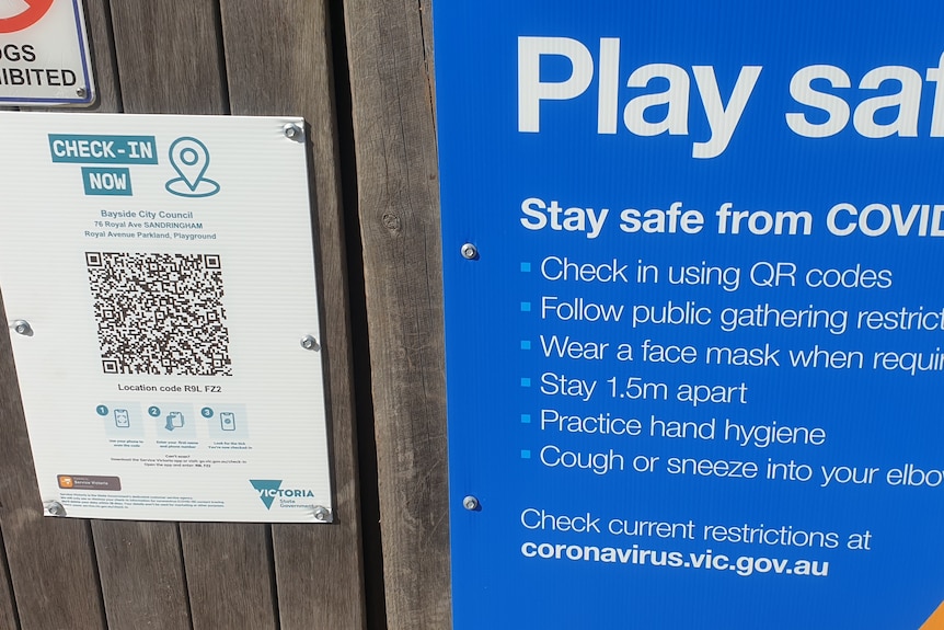A photo of a QR code nailed to the park gate, with COVID SAFE instructions in blue and white. 