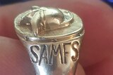 A silver ring with SAMFS inscribed on it