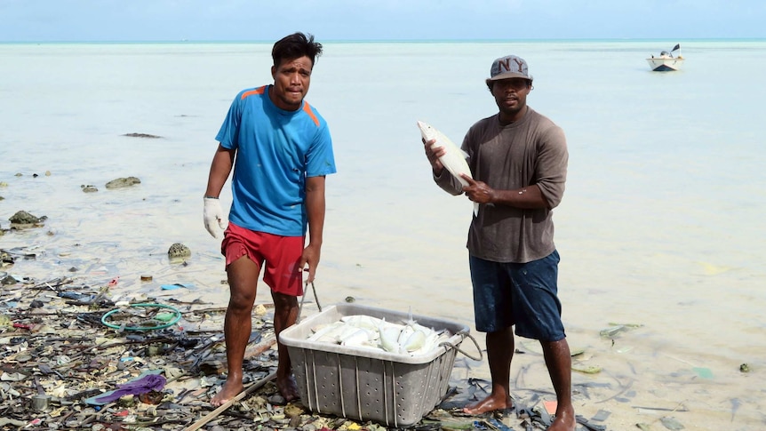 Two young men showing off the fish they have caught