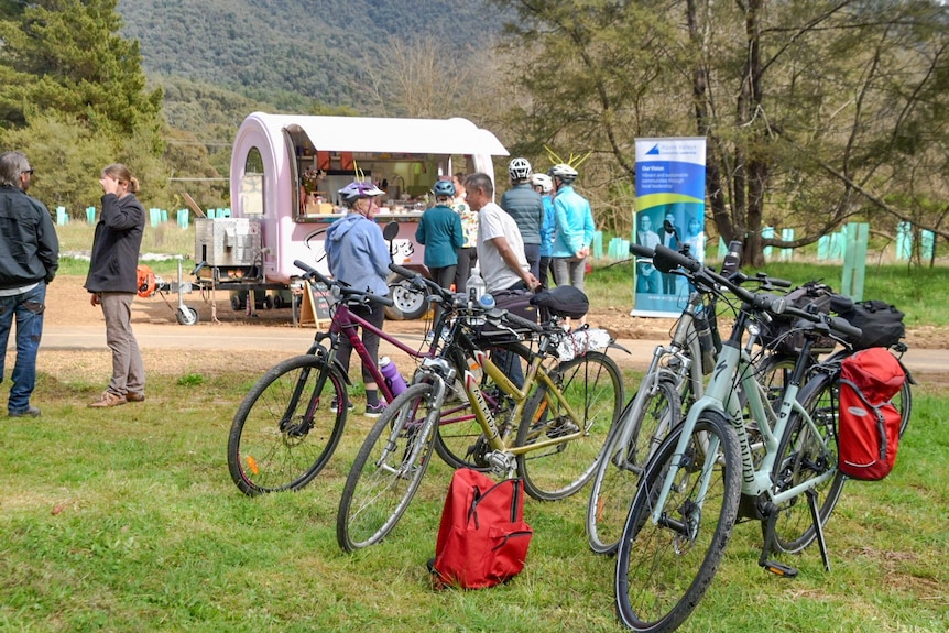 bikes parked in front of small mobile coffee van people standing around drinking coffee