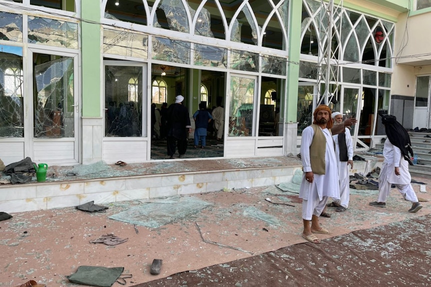 Man stands in front of mosque with shattered windows 