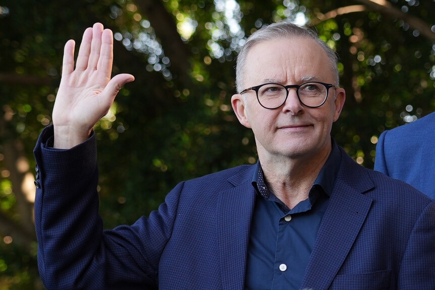 Anthony Albanese stands with an arm raised