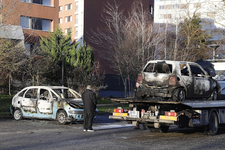 A car breaker removes burnt out cars following New Year's eve.