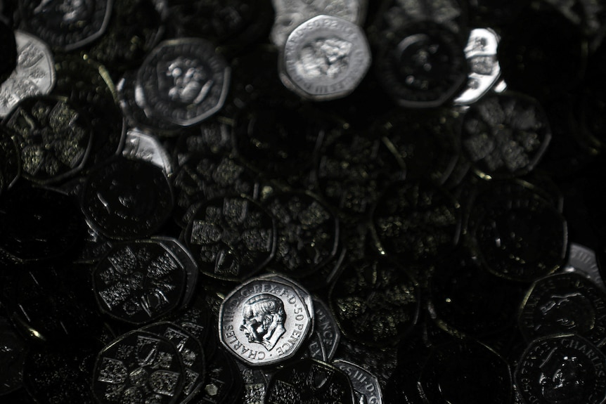 A picture of a pile of coins, one in focus with King Charles III portrait