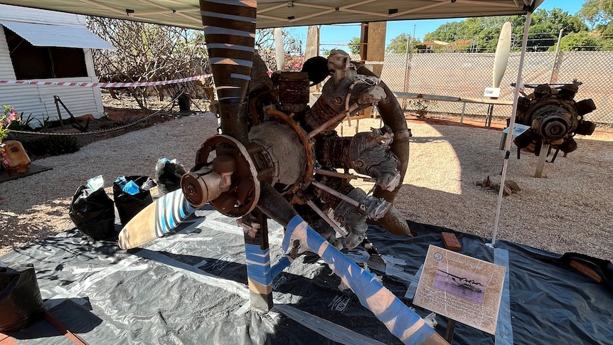 Old plane propeller and engine covered in blue tape.
