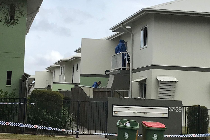 Police forensic officers and police tape outside a unit block where a woman was found stabbed.
