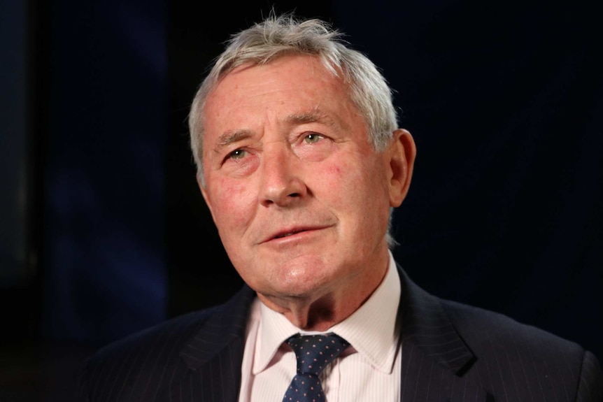 ACT lawyer Bernard Collaery photographed in front of dark background in Canberra