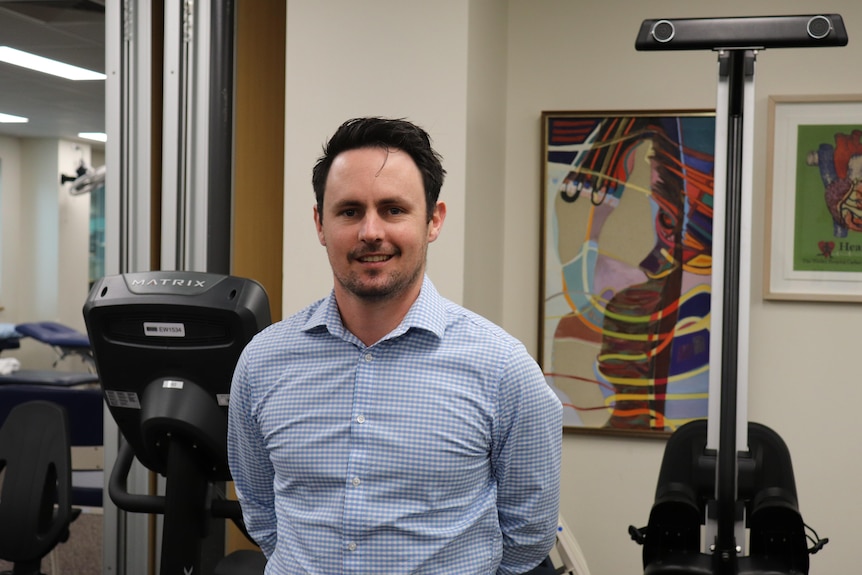 Lead rehabilitation physiotherapist Matt Green who helps long COVID sufferers stand with gym equipment behind him