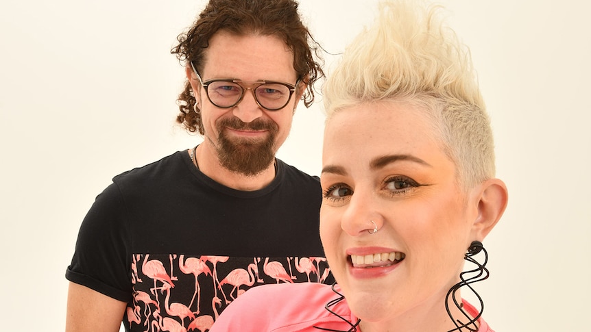 Close up photo of Katie Noonan with nose ring and short blonde hair, Tyrone Noonan with glasses and beard, smiling