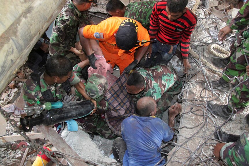 Rescuers pull a survivor from the rubble after Aceh quake