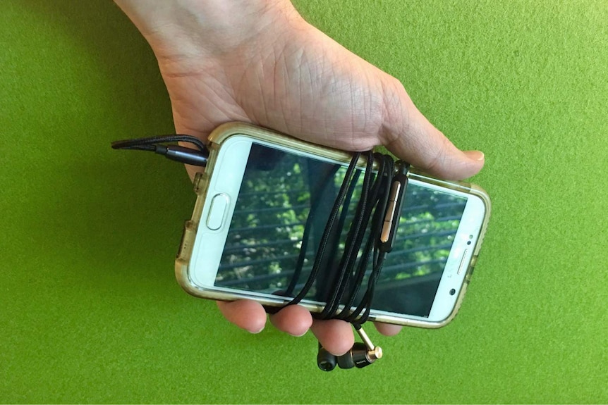 A Samsung phone with headphone cord attached.