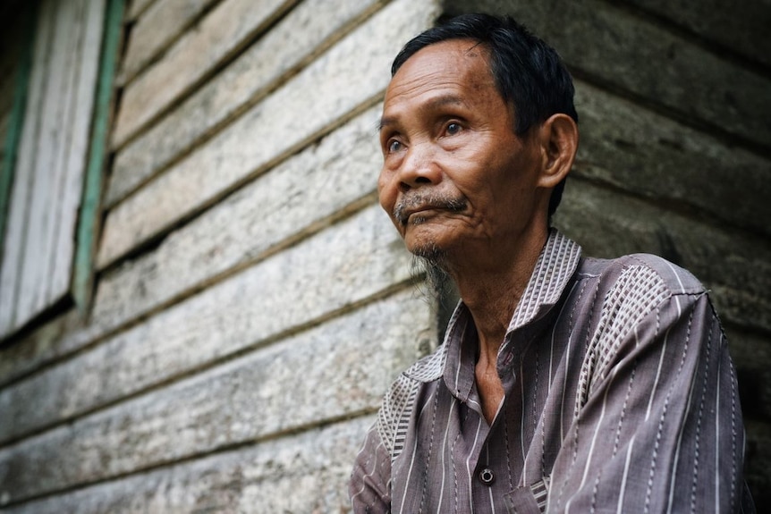 A close up of a man sitting on a stoop.