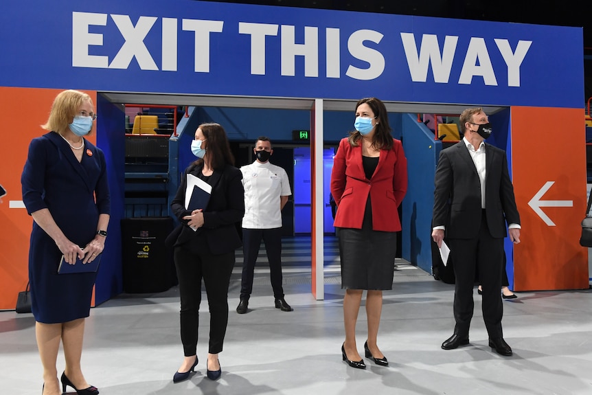   Dr Jeannette Young Yvette D’Ath, Annastacia Palaszczuk and Steven Miles stand under an 'Exit this way' sign.