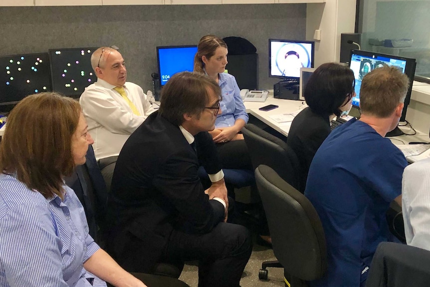 A group of doctors sit around computer screens.