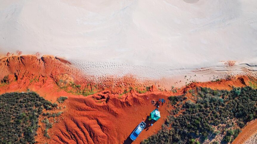 A drone photo of people camping on the red cliffs of Western Australia.