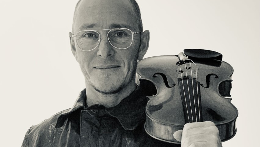 A black and white photo of Ed Ayres, holding a viola on his shoulder.