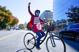 A woman on a bike with her fist in the air and a sign on her chest reading 'count every vote'