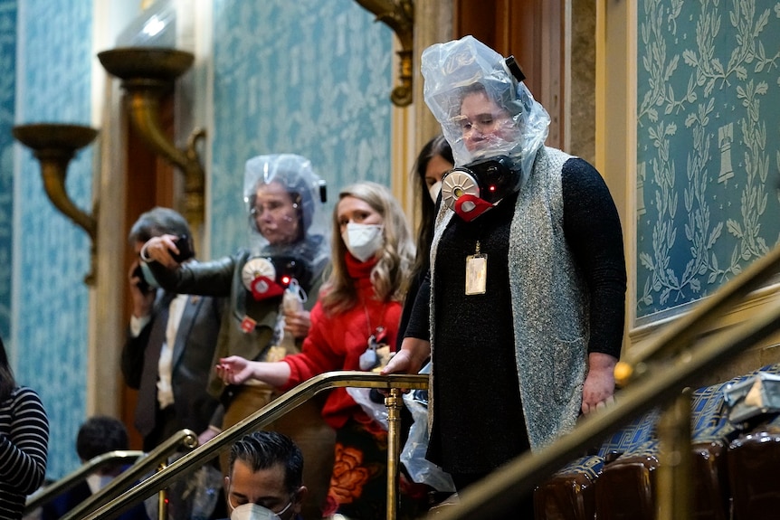 Women wearing gas masks and face masks in the House Chamber at the US Capitol.