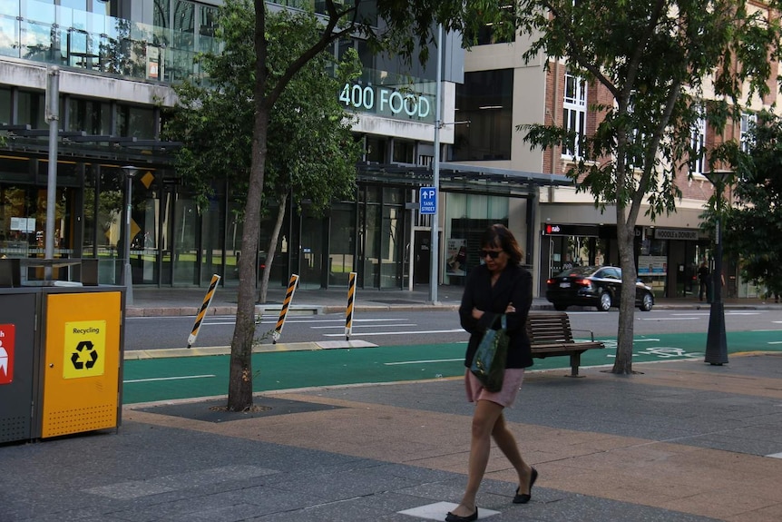 A woman feels the cold walking in a street in Brisbane's CBD on May 1, 2020, during the coronavirus pandemic.