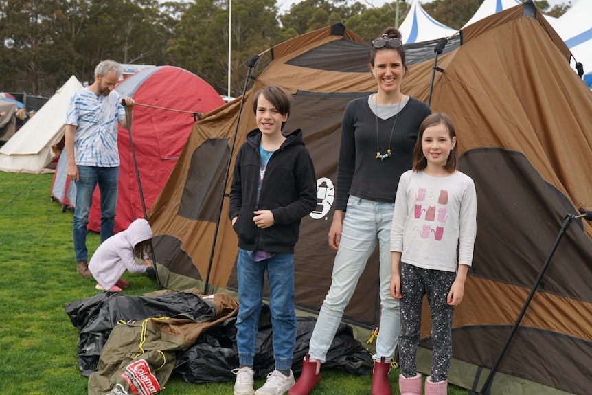 семья стоит перед мокрой палаткой