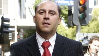 Tony Mokbel, in a dark suit and red tie, arrives at court.