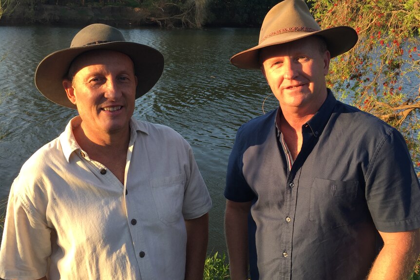 Rod Bruem and Phil Terry smile for the camera in front of a river