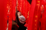 A woman reads ribbons at a wishing tree 