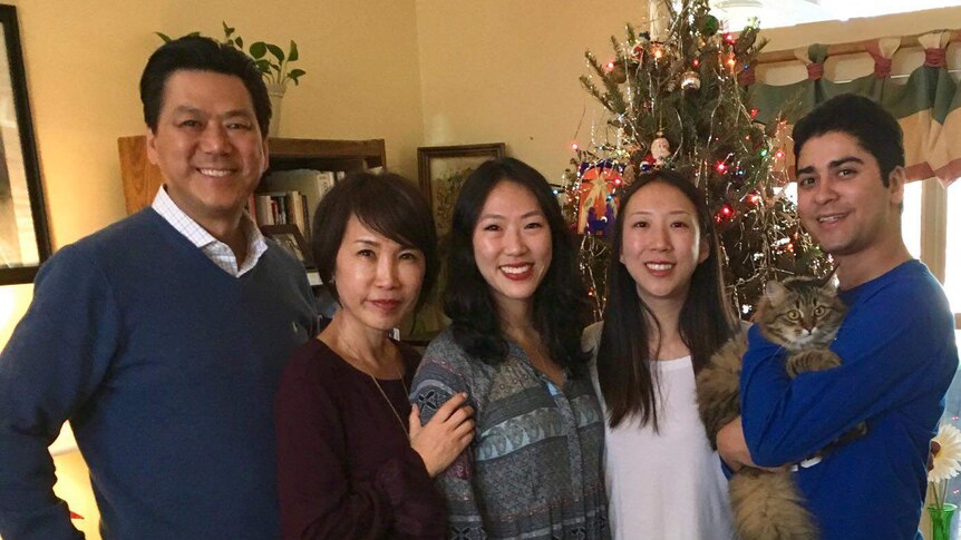 Calvin Chin with his family in front of a Christmas tree.